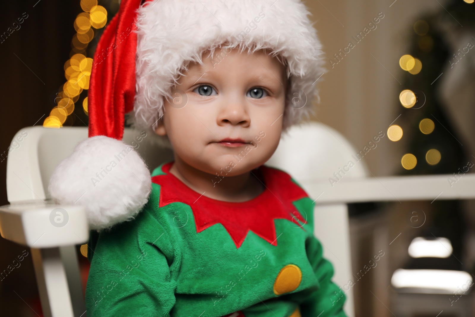 Photo of Baby in cute elf costume sitting on chair at home. Christmas outfit