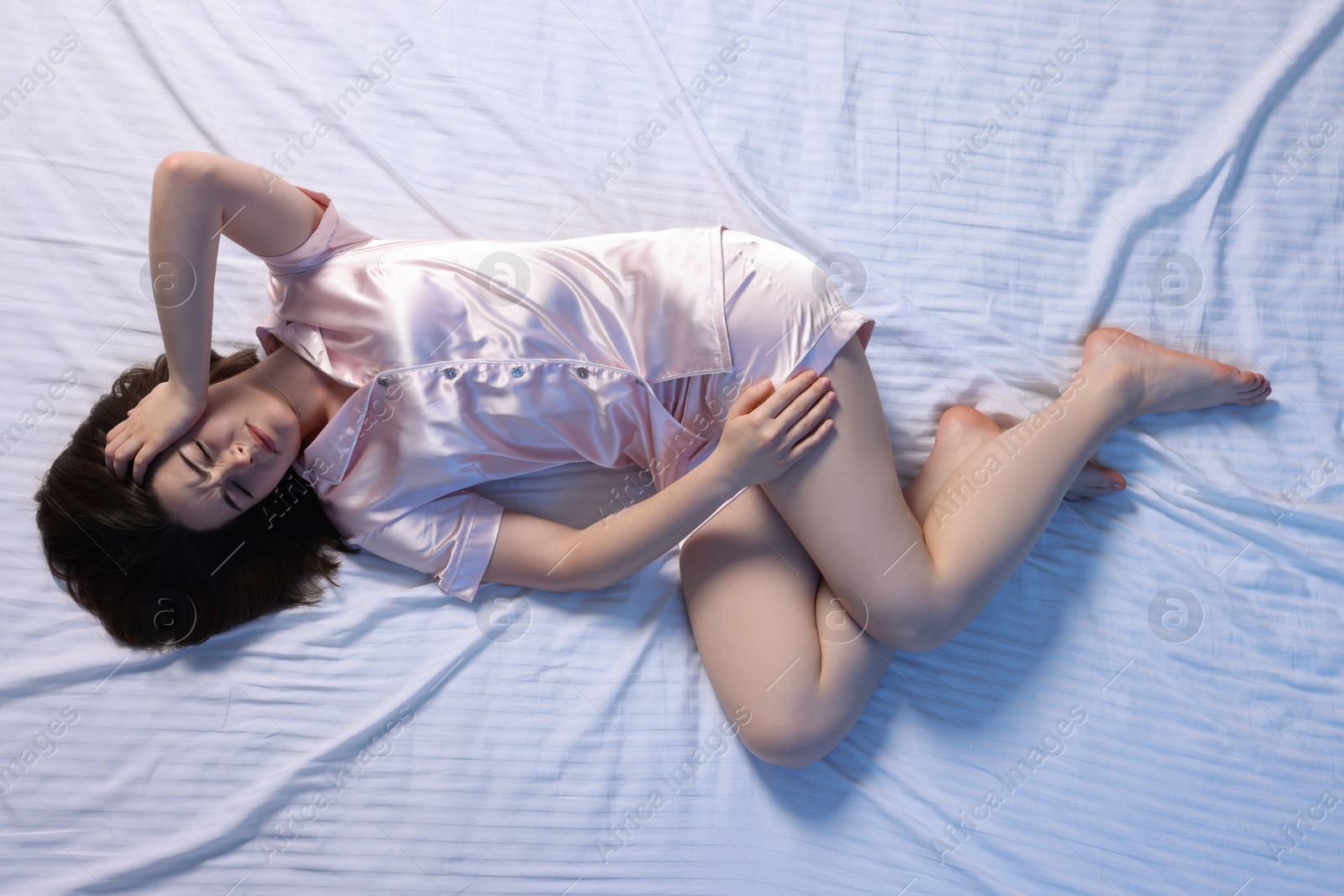 Photo of Young woman suffering from insomnia in bed, top view