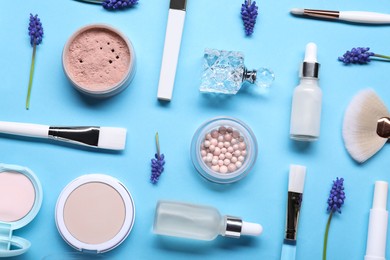 Photo of Flat lay composition with different makeup products and beautiful spring flowers on light blue background