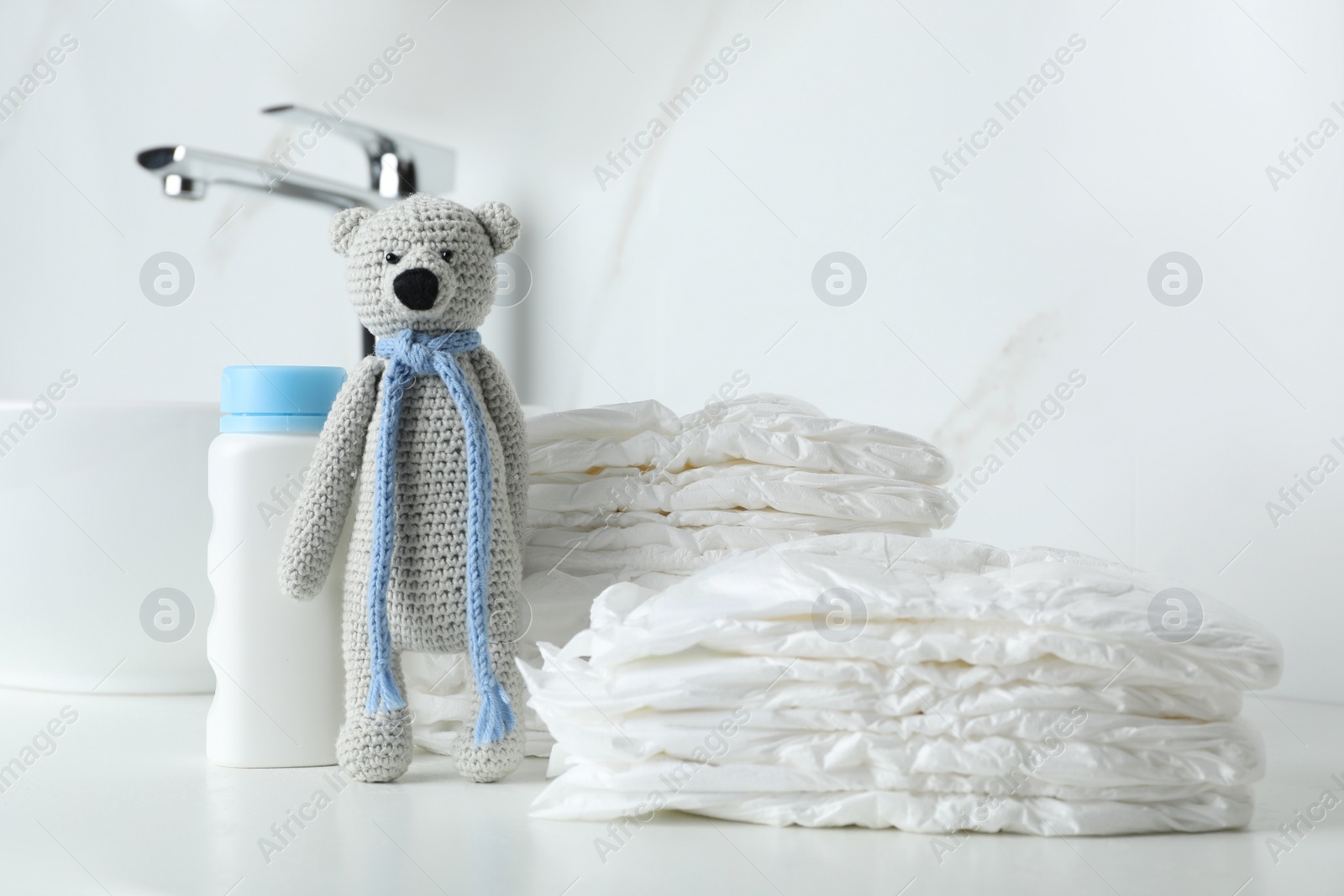Photo of Stacks of diapers and toy bear on counter in bathroom