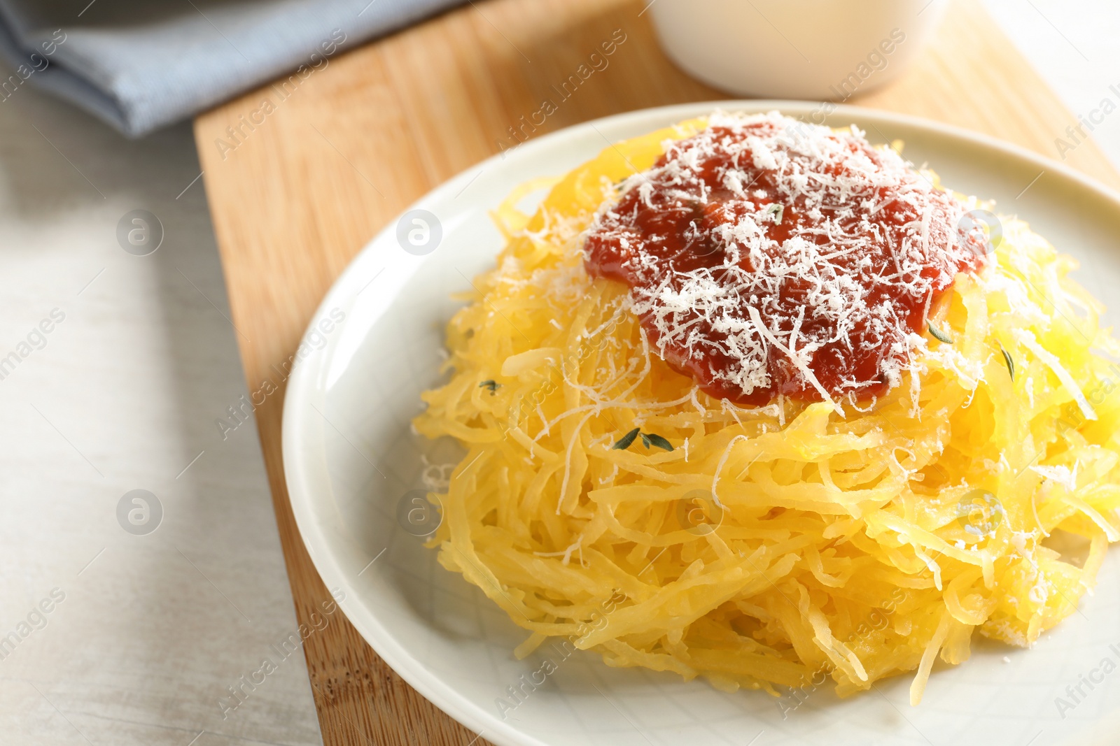 Photo of Cooked spaghetti squash served with sauce and cheese on plate, closeup