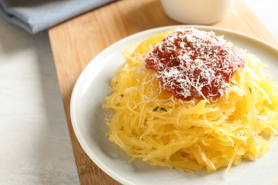 Photo of Cooked spaghetti squash served with sauce and cheese on plate, closeup