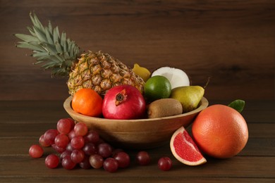 Photo of Fresh ripe fruits and bowl on wooden table