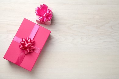 Photo of Pink gift boxes on white wooden table, flat lay. Space for text
