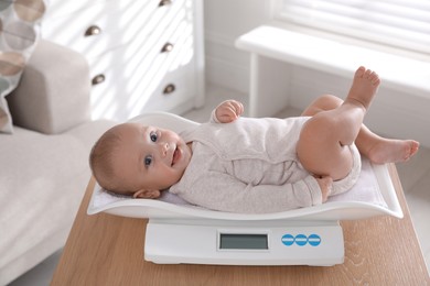 Cute little baby lying on scales at home