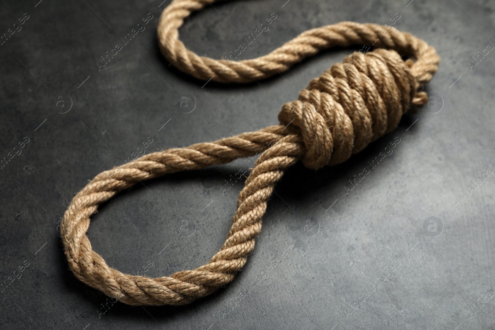 Photo of Rope noose with knot on grey table, closeup