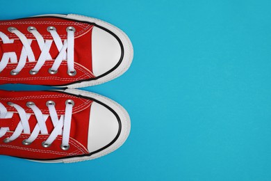 Pair of new stylish red sneakers on light blue background, flat lay. Space for text