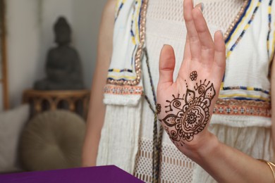 Photo of Woman with henna tattoo on palm indoors, closeup and space for text. Traditional mehndi ornament