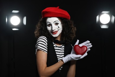 Photo of Young woman in mime costume with red heart figure performing on stage