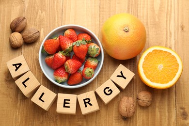 Image of Food allergy. Walnuts, strawberries, citrus fruits and cubes on wooden table, flat lay