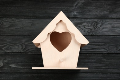 Photo of Beautiful bird house on black wooden table, top view
