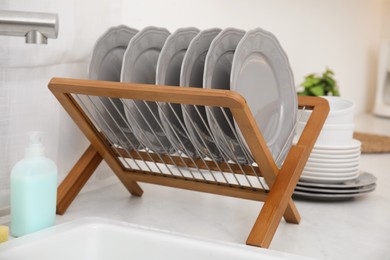 Clean dishes on wooden drying rack in stylish kitchen