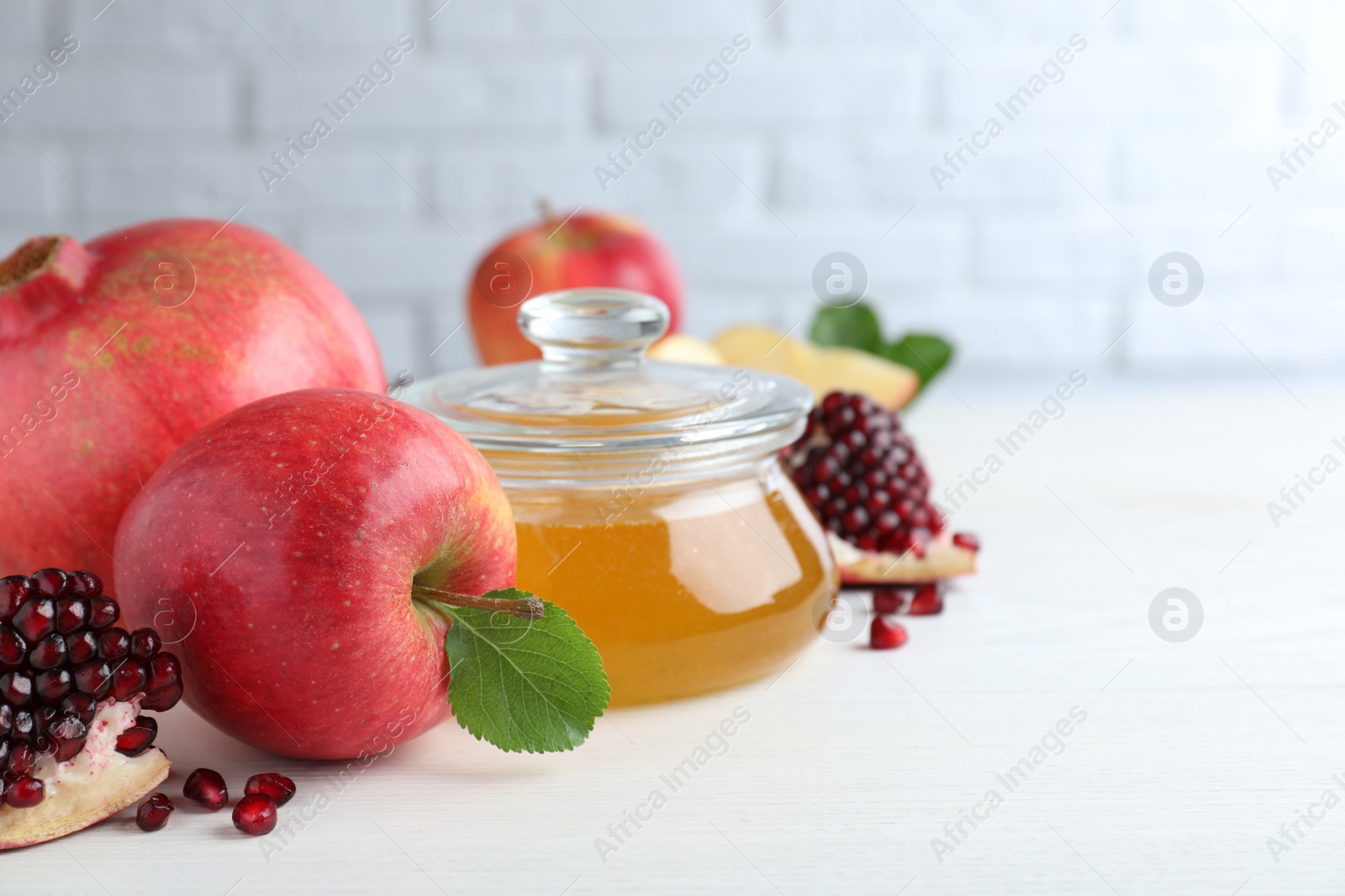 Photo of Honey, pomegranate and apples on white wooden table. Rosh Hashana holiday