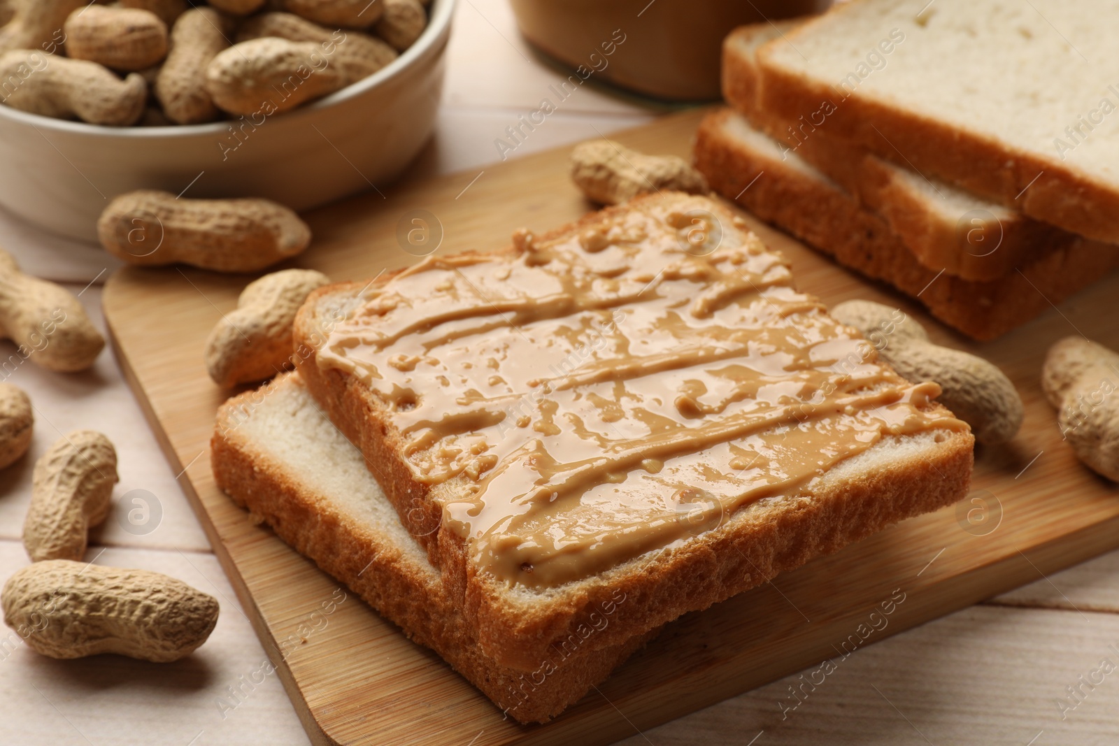 Photo of Delicious toasts with peanut butter and nuts on light wooden table, closeup