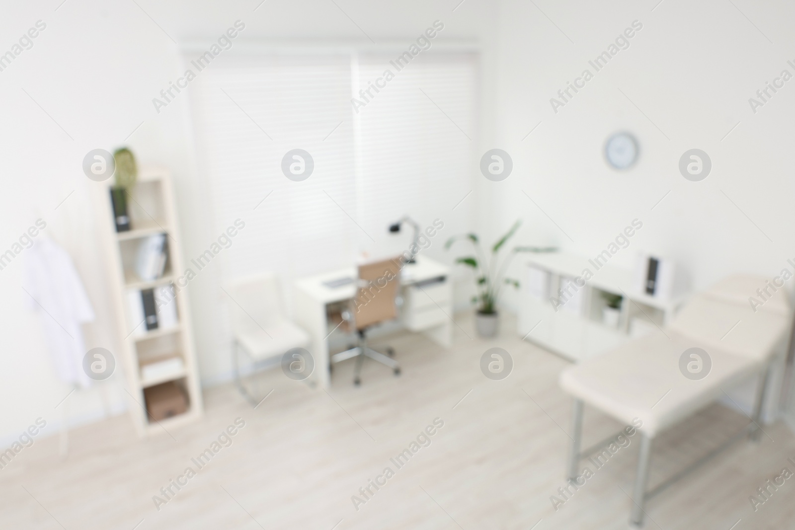 Photo of Blurred view of modern medical office with doctor's workplace and examination table in clinic