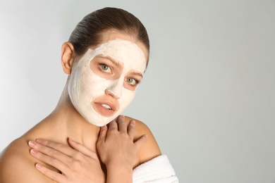 Photo of Beautiful woman with clay mask on her face against grey background. Space for text