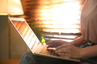 Woman working with modern laptop indoors, closeup