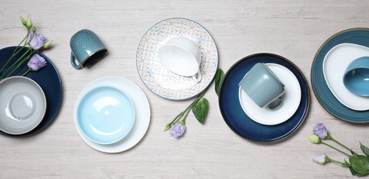 Photo of Flat lay composition with beautiful dishware and flowers on white wooden table