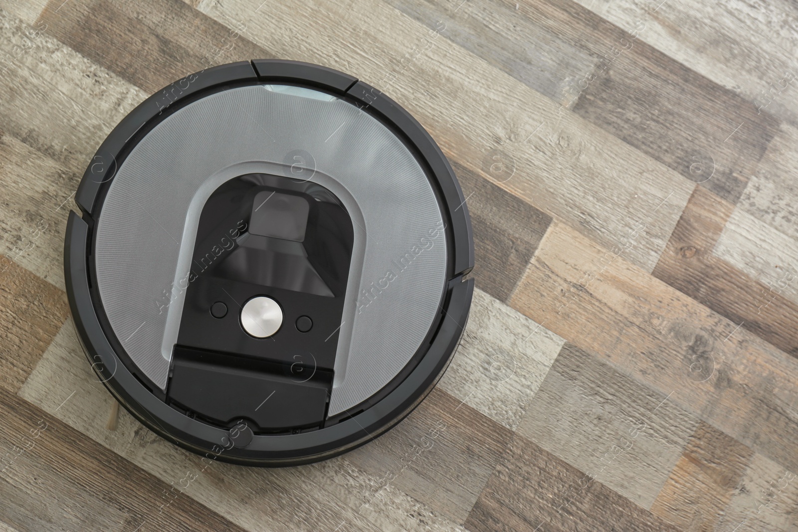 Photo of Modern robotic vacuum cleaner on wooden floor, top view. Space for text