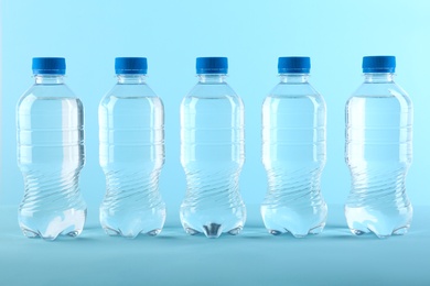 Photo of Row of plastic bottles with water on color background