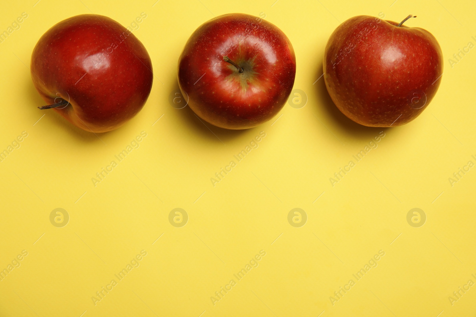 Photo of Flat lay composition with ripe juicy red apples on yellow background, space for text