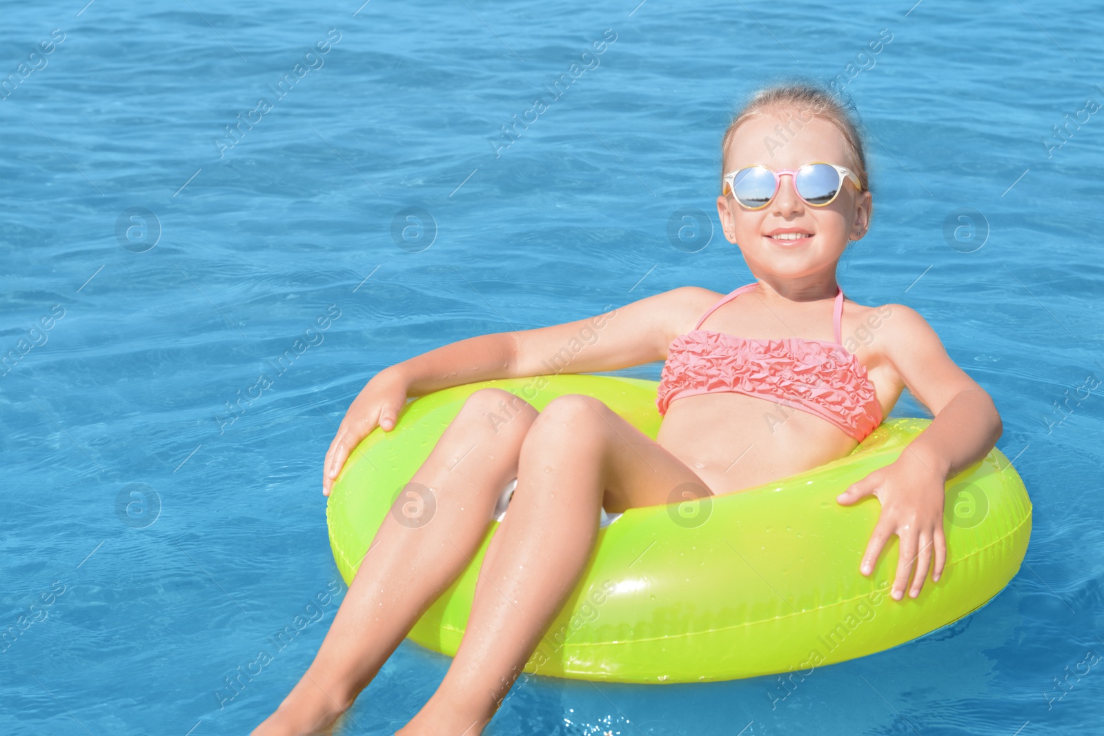 Photo of Happy little girl with inflatable ring in sea on sunny day