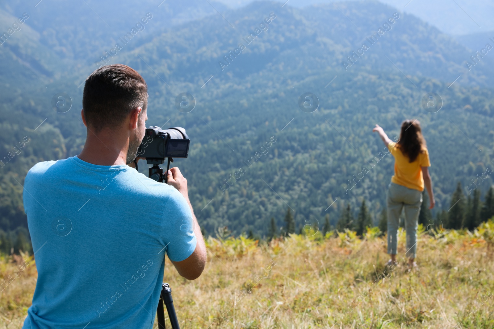 Photo of Professional photographer taking picture of woman in mountains, back view