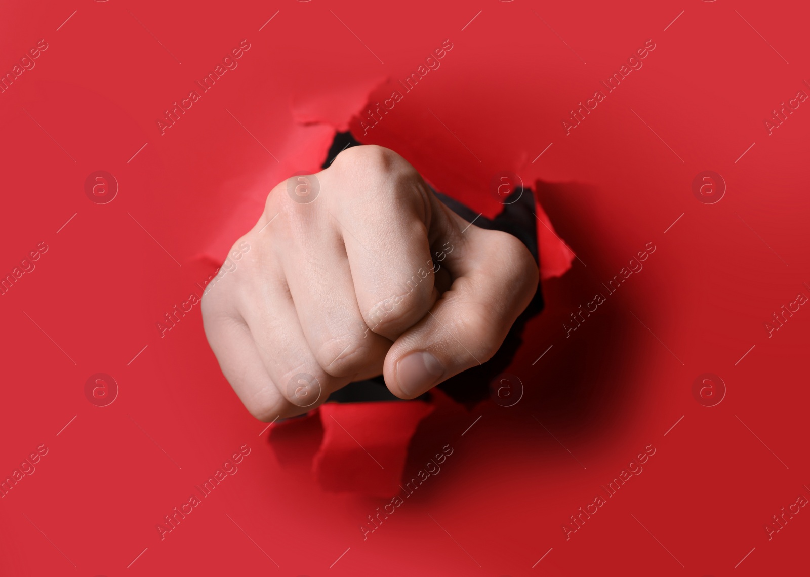 Photo of Man breaking through red paper with fist, closeup