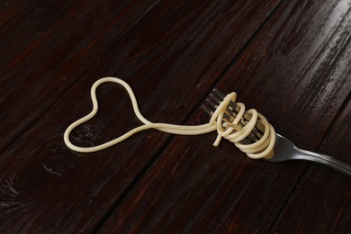 Photo of Heart made of tasty spaghetti and fork on wooden table