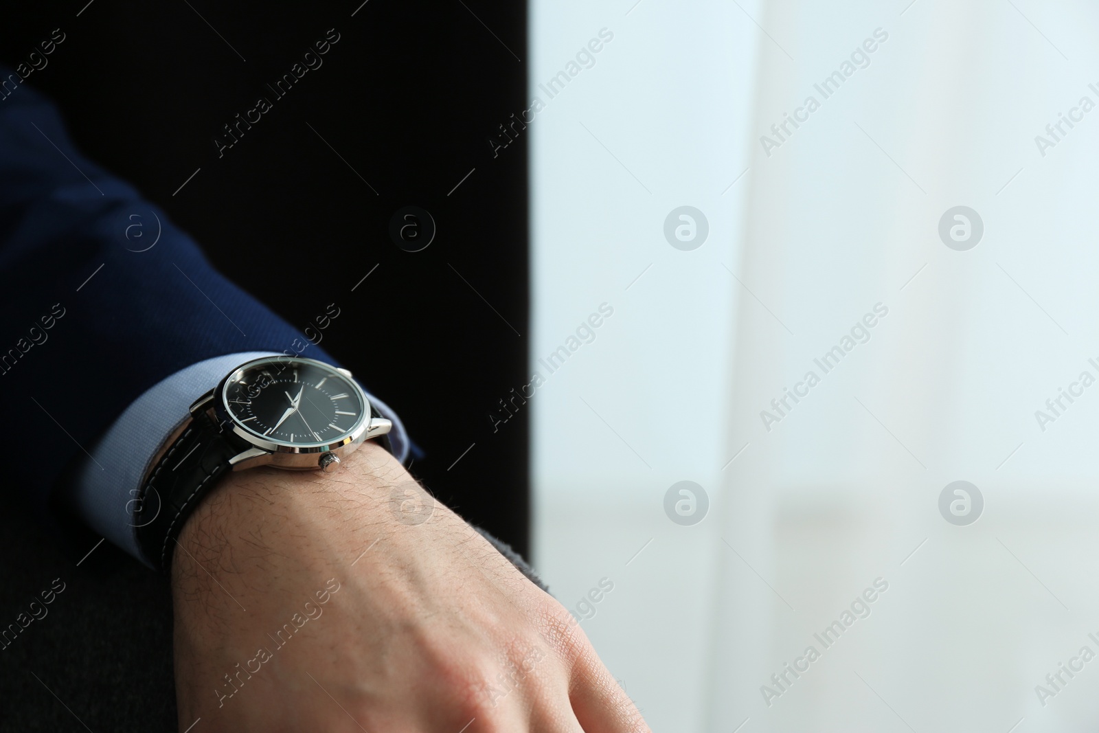 Photo of Businessman with luxury wrist watch on blurred background, closeup. Space for text