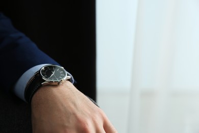 Photo of Businessman with luxury wrist watch on blurred background, closeup. Space for text