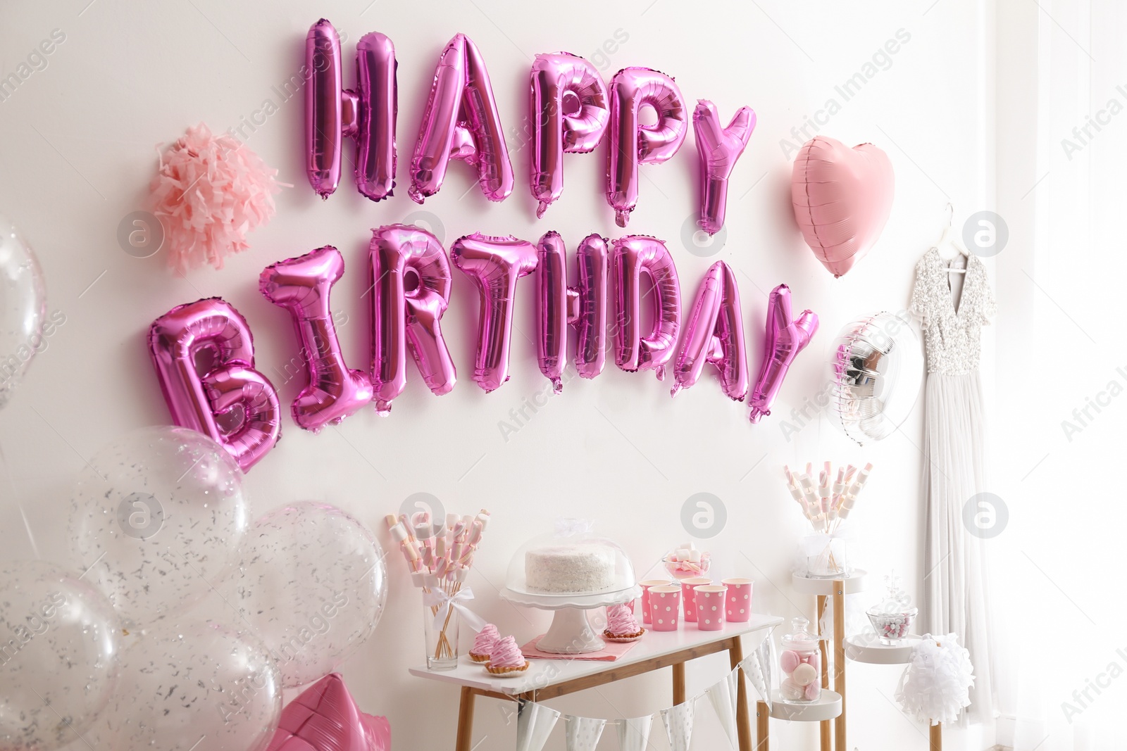 Photo of Phrase HAPPY BIRTHDAY made of pink balloon letters in decorated room