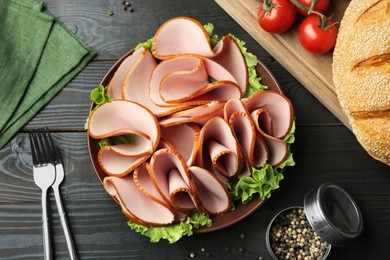 Photo of Slices of delicious boiled sausage and other products on dark wooden table, flat lay