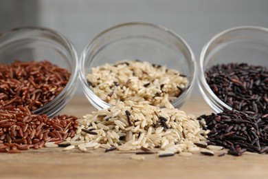Photo of Different types of rice on wooden table, closeup