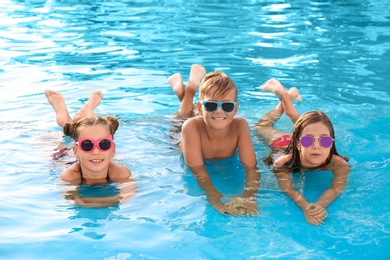 Happy cute children in swimming pool on sunny day