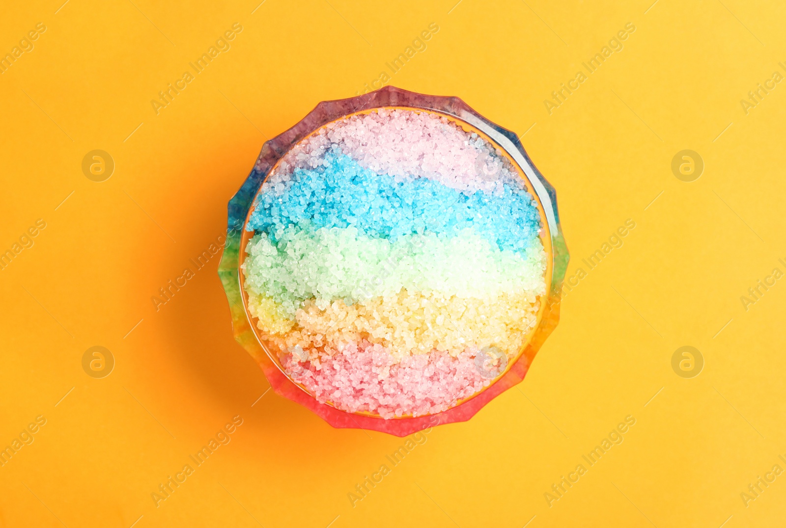 Photo of Rainbow shaving ice in glass dessert bowl on orange background, top view