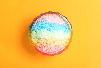 Photo of Rainbow shaving ice in glass dessert bowl on orange background, top view