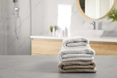 Photo of Stack of clean towels on grey stone table in bathroom. Space for text