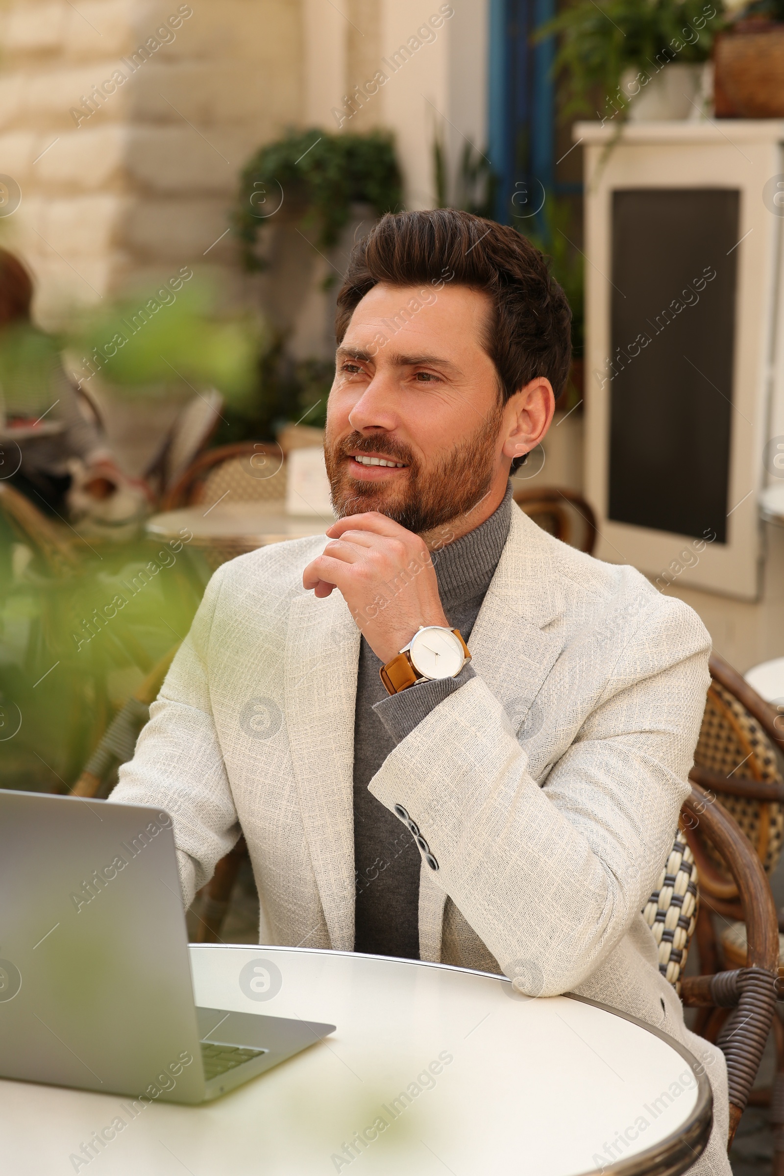 Photo of Man with laptop at table in outdoor cafe