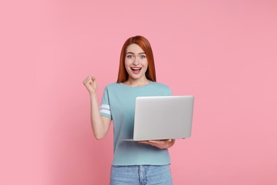 Photo of Happy young woman with laptop on pink background