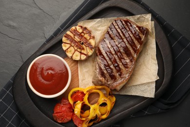 Photo of Delicious grilled beef steak with spices and tomato sauce on dark gray table, top view