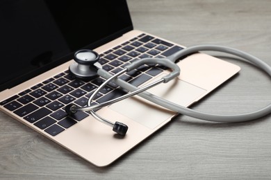 Photo of Laptop with stethoscope on wooden table, closeup