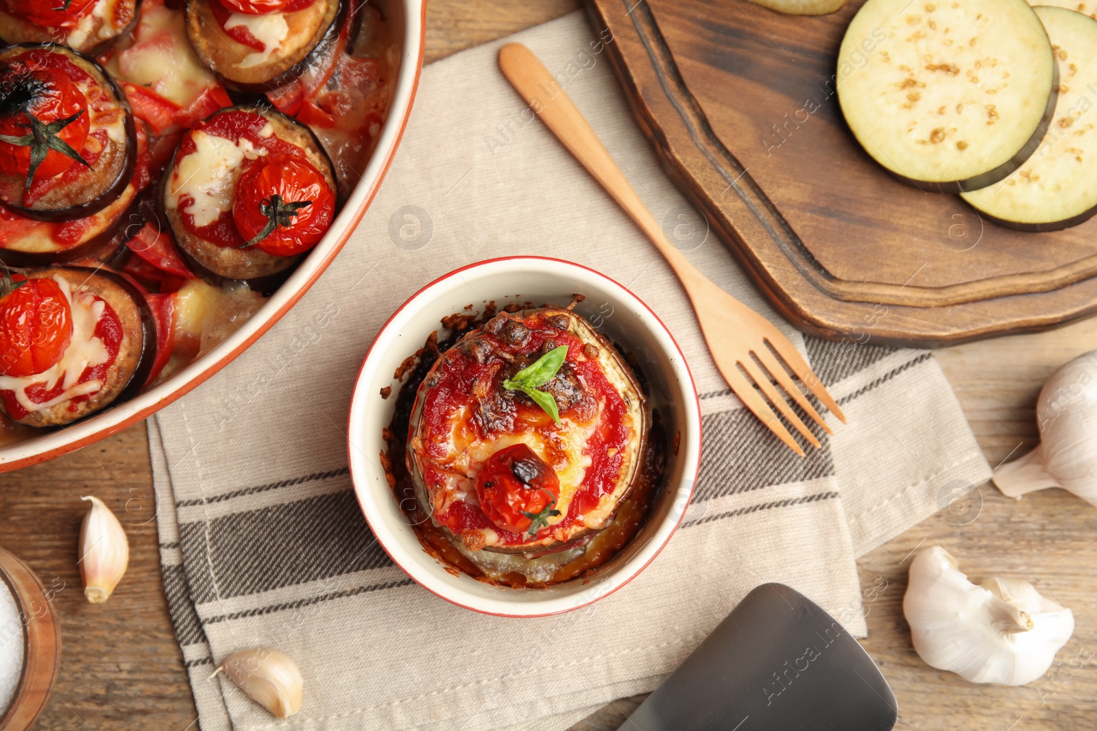 Photo of Baked eggplant with tomatoes, cheese and basil served on wooden table, flat lay