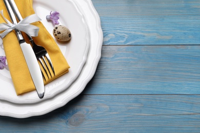 Photo of Festive Easter table setting with egg on blue wooden background, top view. Space for text