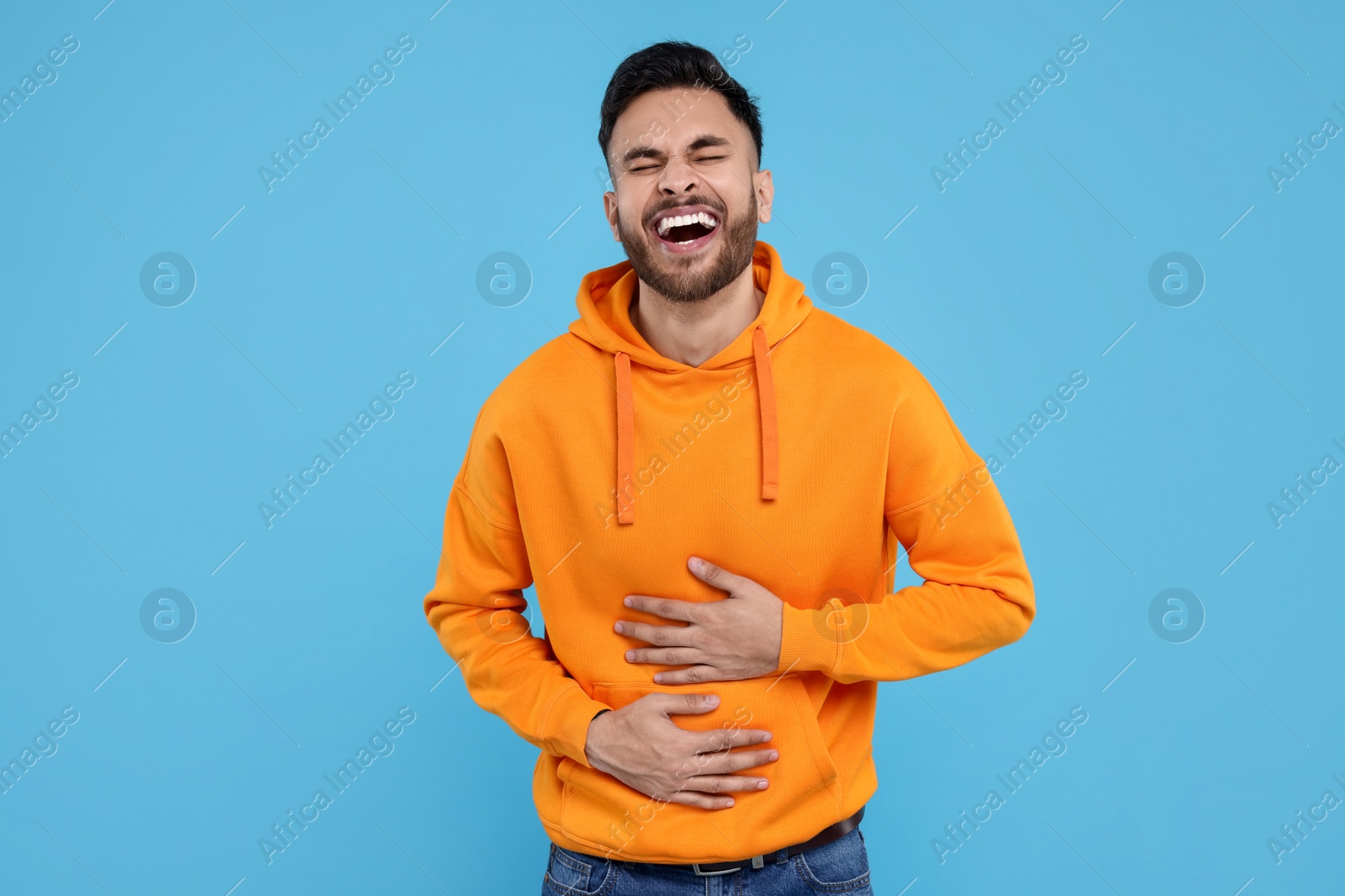 Photo of Handsome young man laughing on light blue background