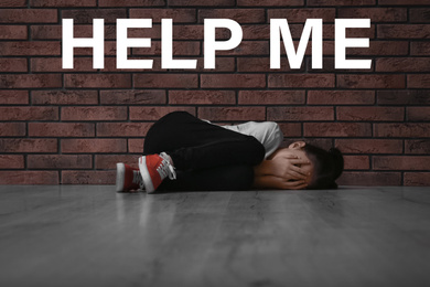 Image of Scared little girl lying on floor near brick wall and text HELP ME
