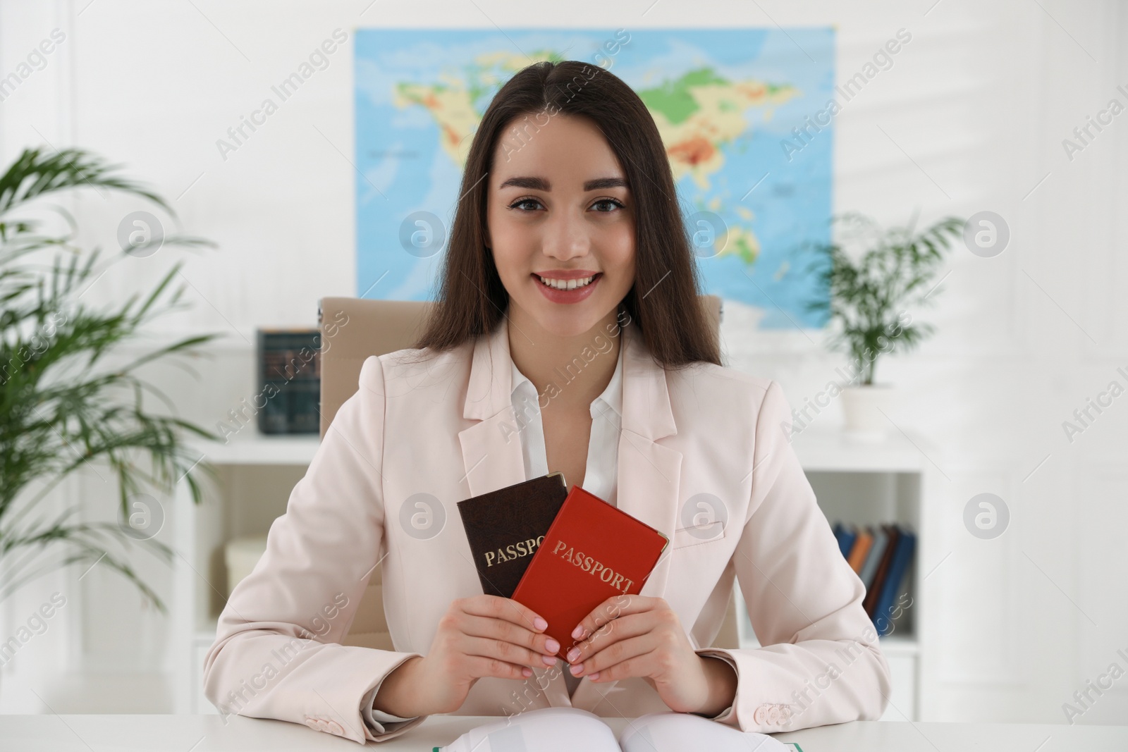 Photo of Happy manager holding passports at desk in travel agency