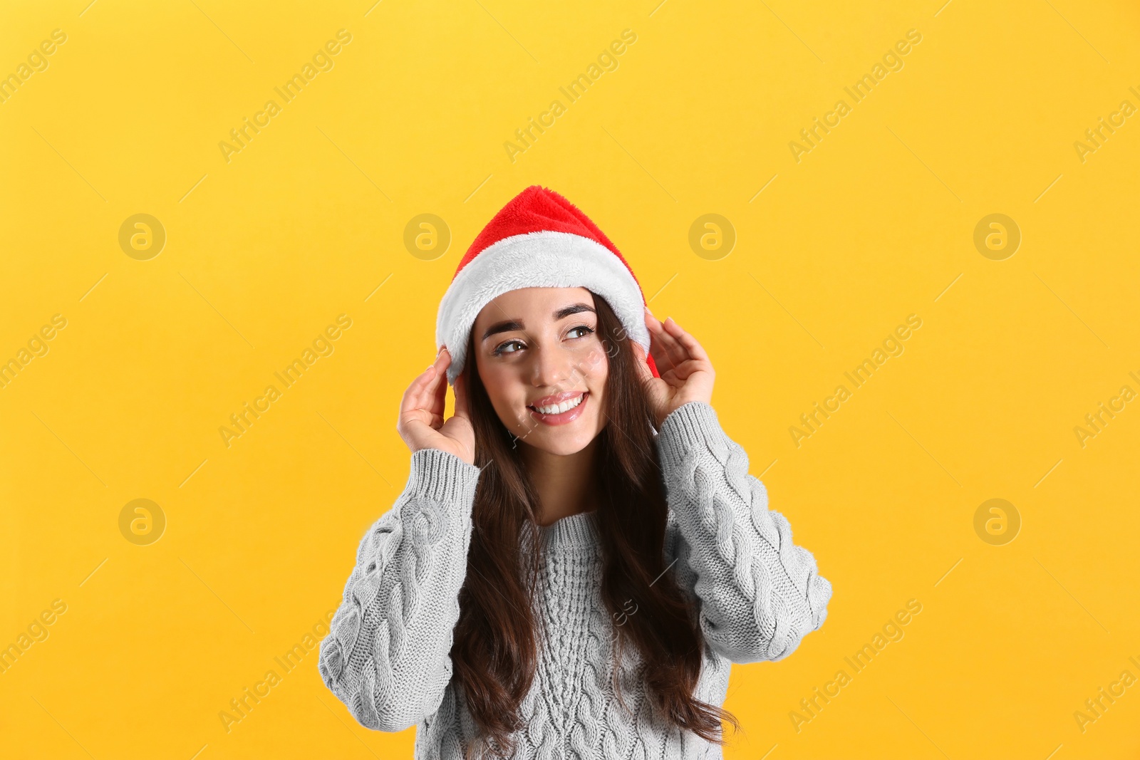 Photo of Beautiful woman wearing Santa Claus hat on yellow background