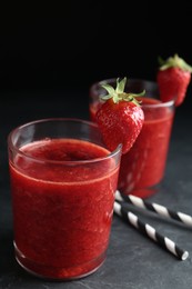 Photo of Tasty strawberry smoothie in glass on black table
