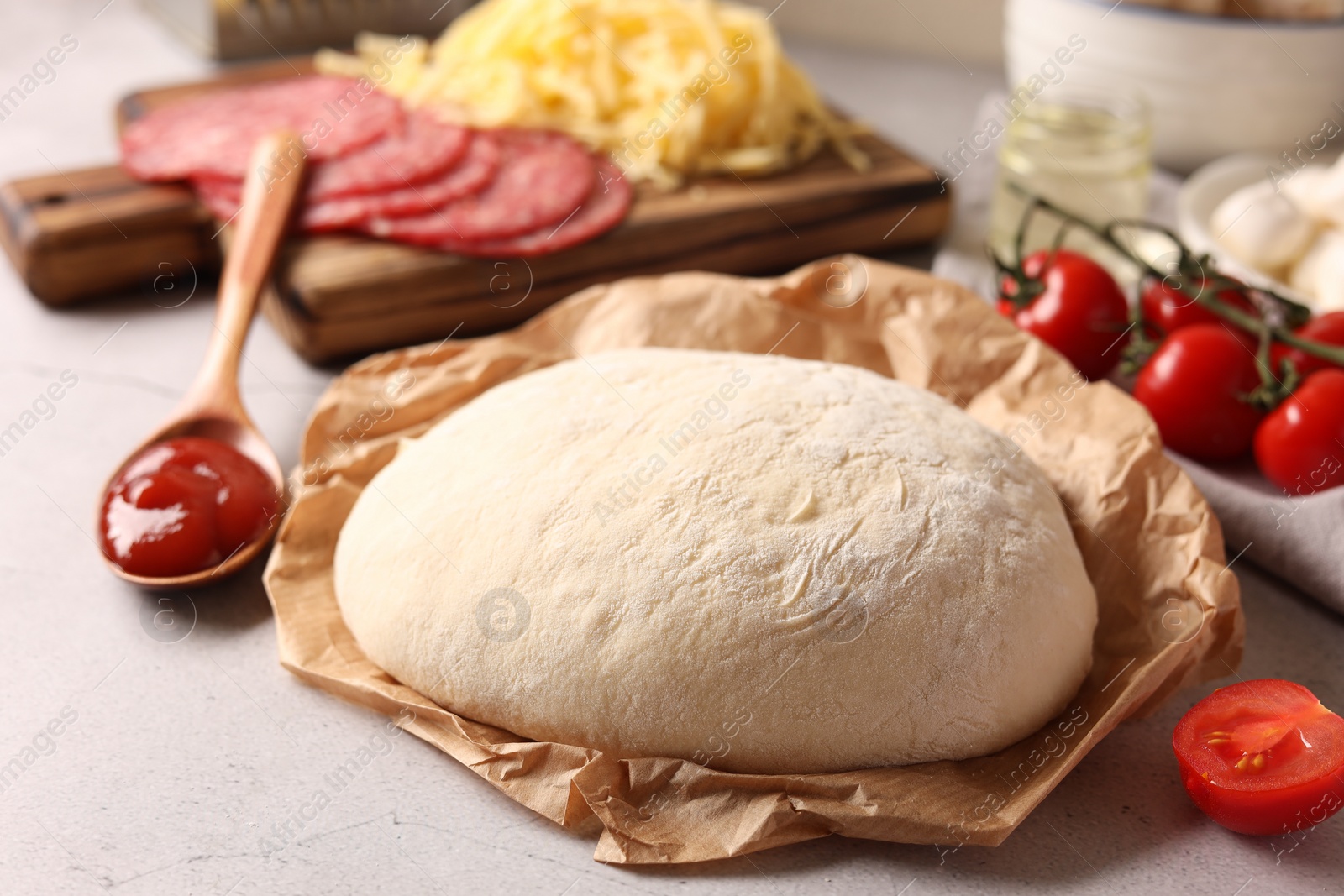 Photo of Pizza dough and products on gray textured table, closeup